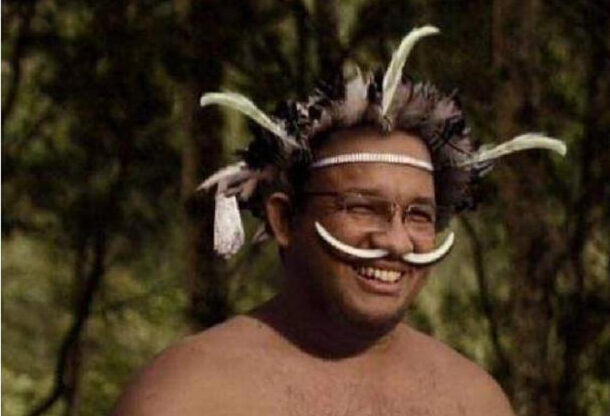 Foto meme Anies Baswedan memakai pakaian adat Papua dan memakai koteka